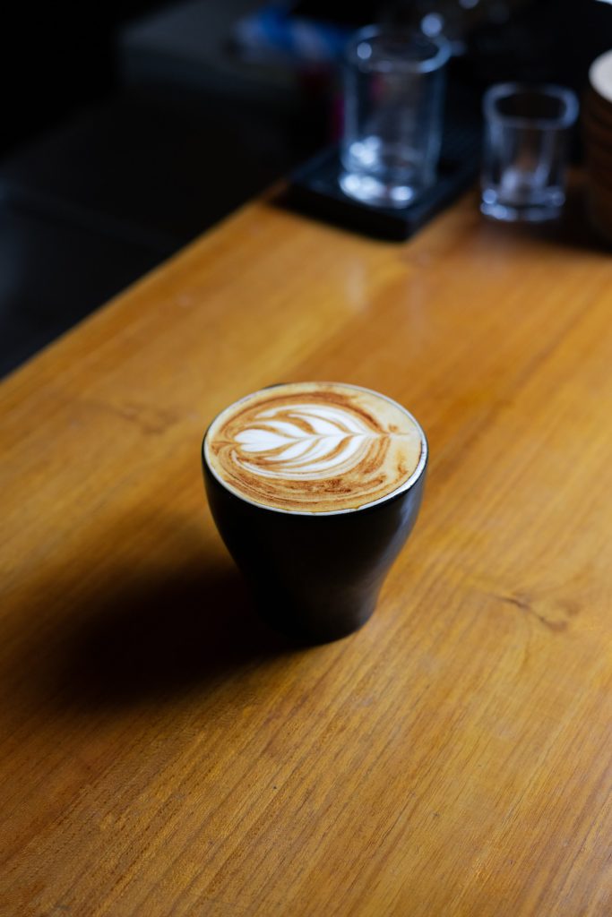 Latte art coffee on a wooden table at Camino Bali