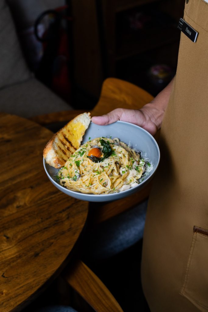 Server bringing a pasta dish to the table at Camino Bali