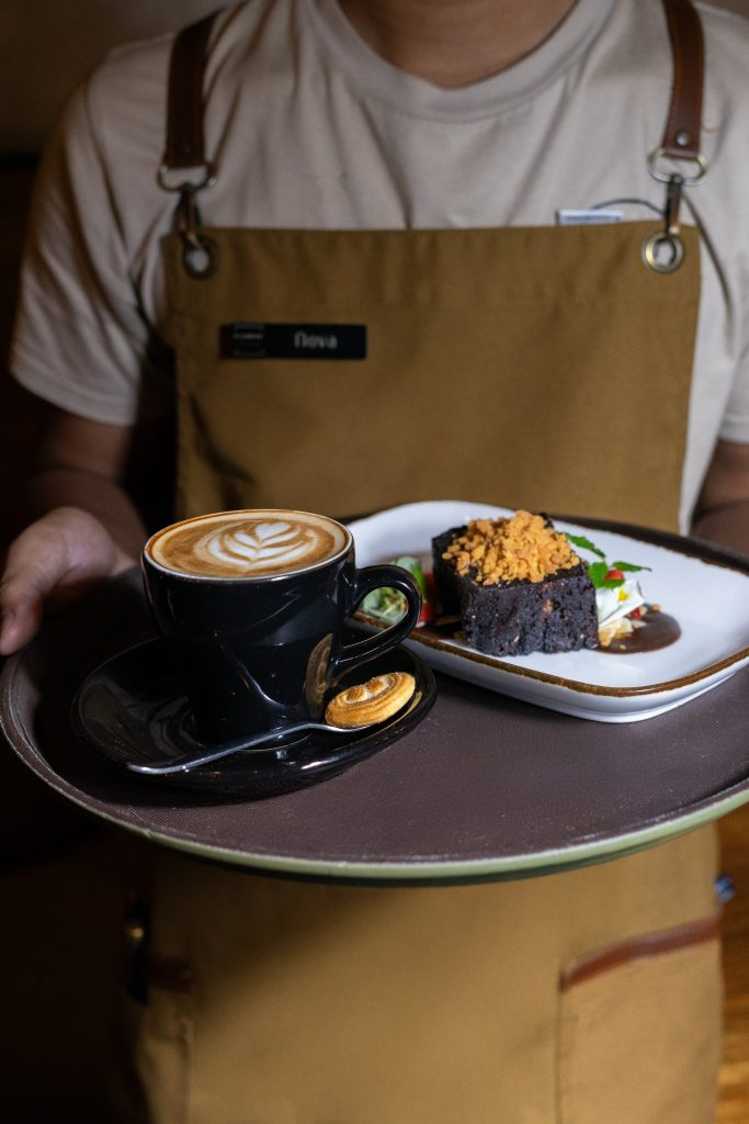 Server carrying coffee and dessert at Camino Resto & Bar
